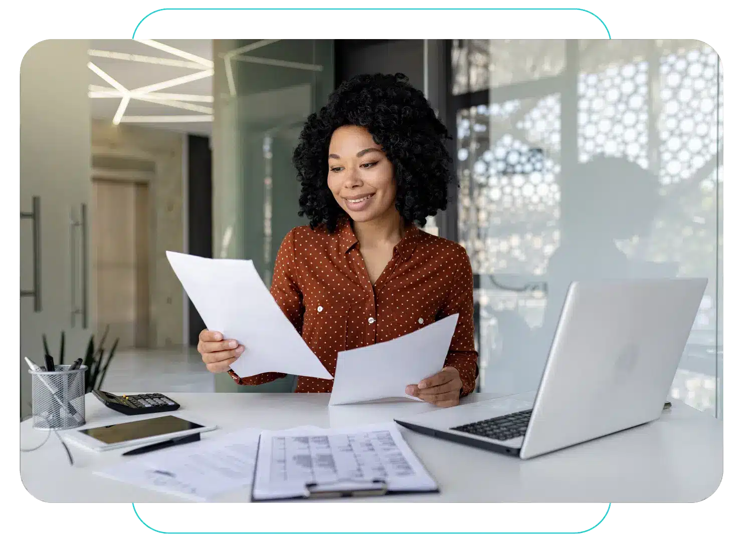 Smiling woman reviewing documents at a desk with a laptop and calculator for Propio HealthTrust document translation